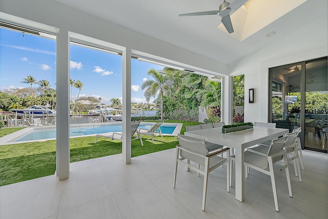 sunroom / solarium featuring a water view, ceiling fan, vaulted ceiling, and a wealth of natural light