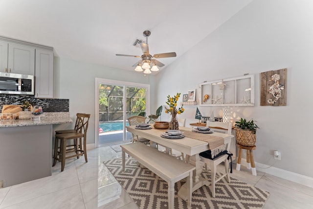 dining space with lofted ceiling, light tile patterned floors, and ceiling fan