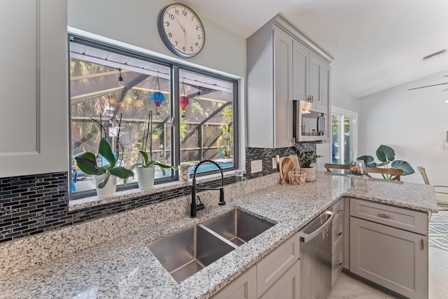 kitchen featuring sink, gray cabinets, kitchen peninsula, stainless steel appliances, and decorative backsplash