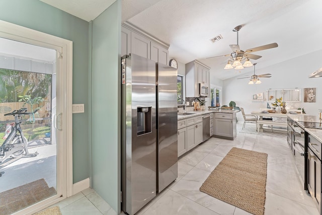 kitchen with stainless steel appliances, sink, gray cabinets, and vaulted ceiling