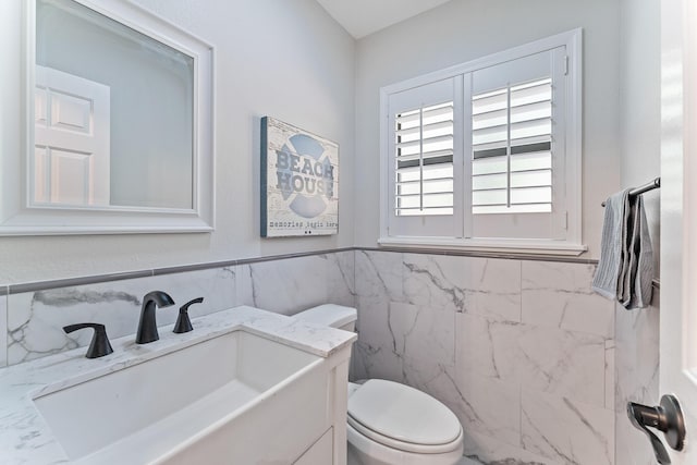 bathroom with vanity, tile walls, and toilet