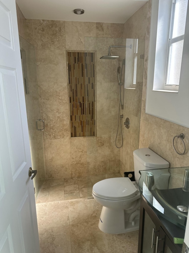 bathroom featuring tiled shower, vanity, toilet, and tile walls