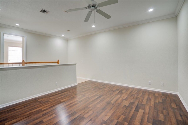 empty room with baseboards, crown molding, visible vents, and wood finished floors