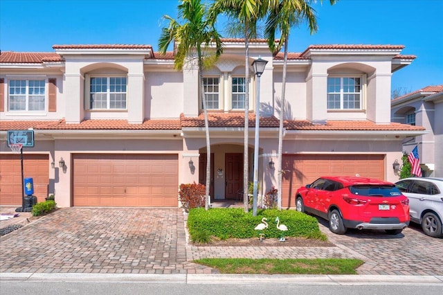 view of front of property featuring a garage, decorative driveway, a tile roof, and stucco siding