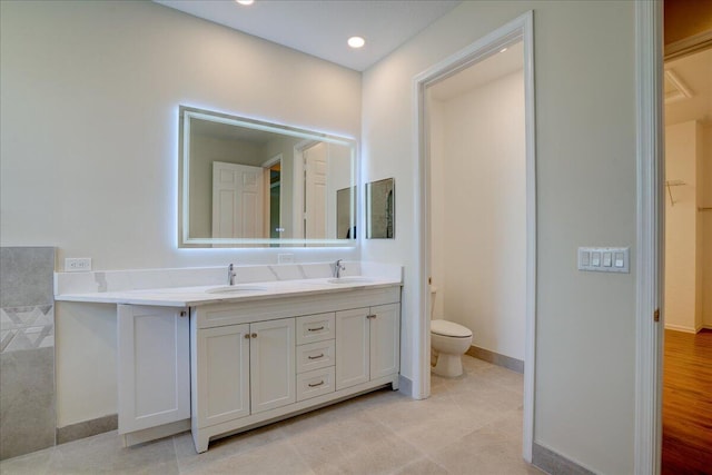 full bath with baseboards, a sink, toilet, and double vanity