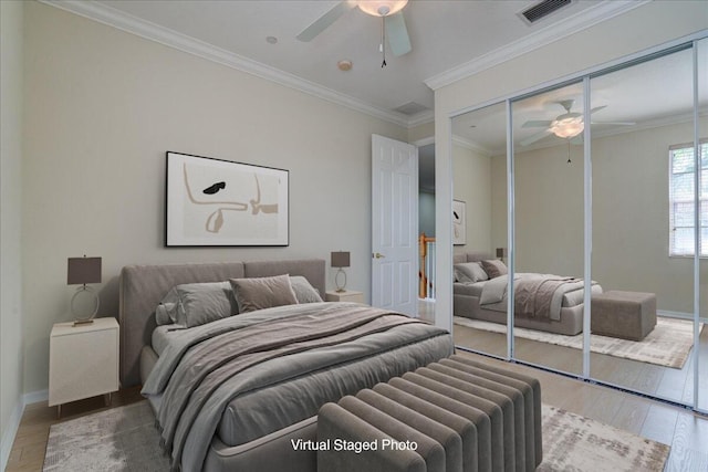 bedroom with wood finished floors, visible vents, baseboards, ornamental molding, and a closet