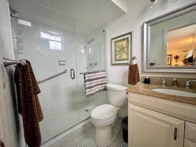 bathroom featuring vanity, tile patterned flooring, a shower with door, and toilet