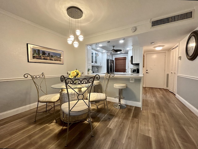 dining area with ornamental molding and dark hardwood / wood-style flooring