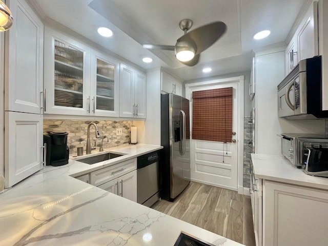 kitchen with sink, white cabinetry, light stone counters, stainless steel appliances, and backsplash