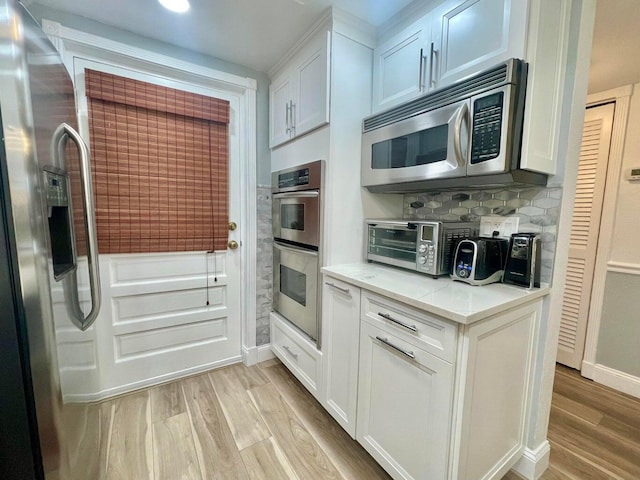 kitchen with light hardwood / wood-style flooring, stainless steel appliances, and white cabinets