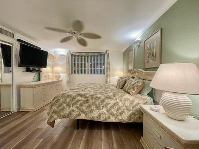 bedroom featuring ceiling fan, ornamental molding, and dark hardwood / wood-style floors