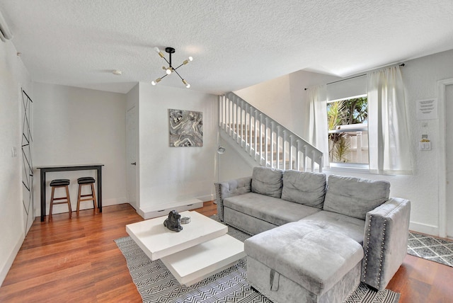 living room with a textured ceiling, stairs, baseboards, and wood finished floors