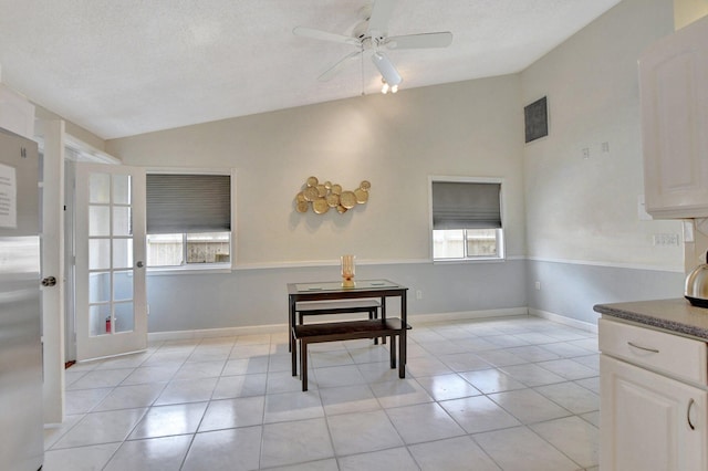 dining space with light tile patterned floors, lofted ceiling, a ceiling fan, a textured ceiling, and baseboards