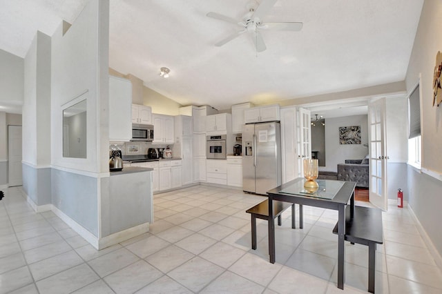 kitchen featuring light tile patterned floors, lofted ceiling, white cabinetry, appliances with stainless steel finishes, and decorative backsplash