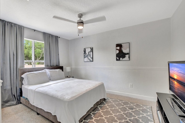 carpeted bedroom featuring ceiling fan, a textured ceiling, and baseboards