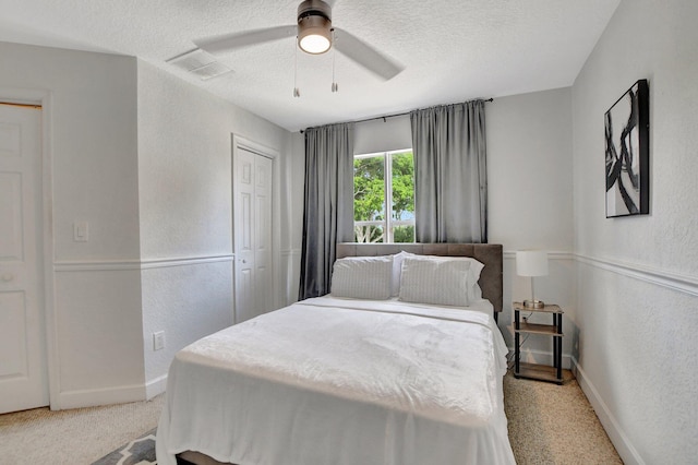 bedroom featuring a textured ceiling, a textured wall, visible vents, baseboards, and a closet