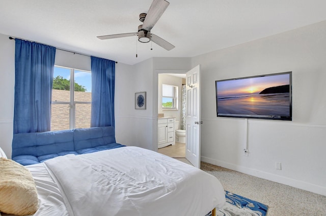 bedroom with a ceiling fan, light carpet, ensuite bath, and baseboards