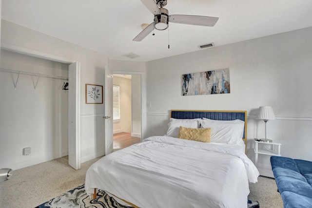 bedroom with baseboards, visible vents, a ceiling fan, light colored carpet, and a closet