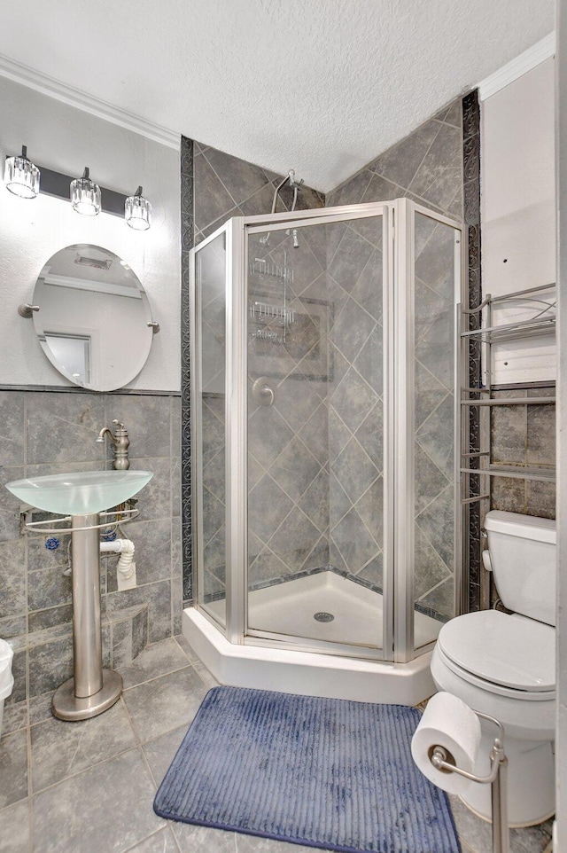 bathroom featuring a textured ceiling, tile patterned flooring, toilet, tile walls, and a shower stall