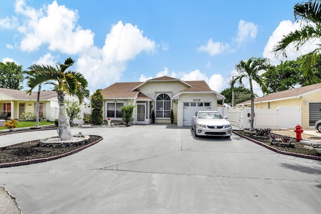 ranch-style house featuring stucco siding, concrete driveway, a gate, fence, and a garage