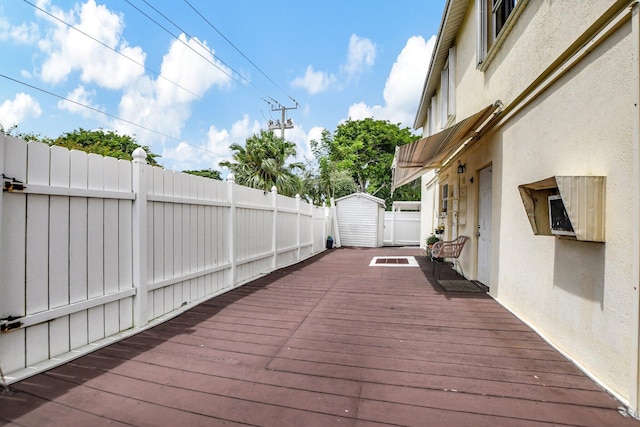 wooden terrace with fence, an outdoor structure, and a storage unit