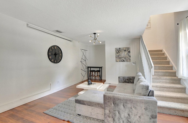 living area featuring an inviting chandelier, visible vents, stairway, and wood finished floors