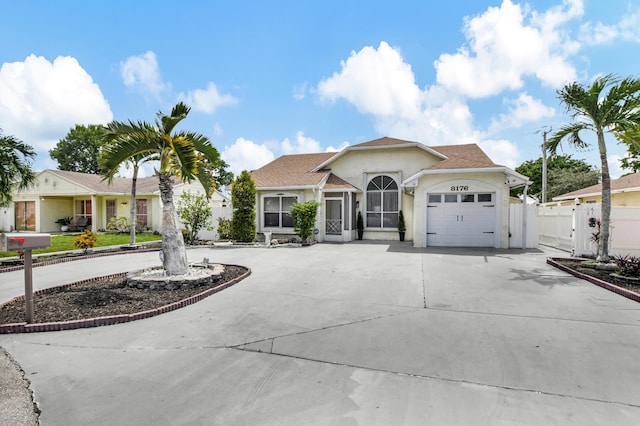 ranch-style house featuring a garage, stucco siding, driveway, and fence