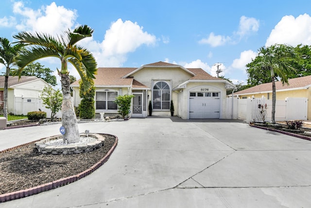 view of front facade featuring driveway, an attached garage, a gate, and fence