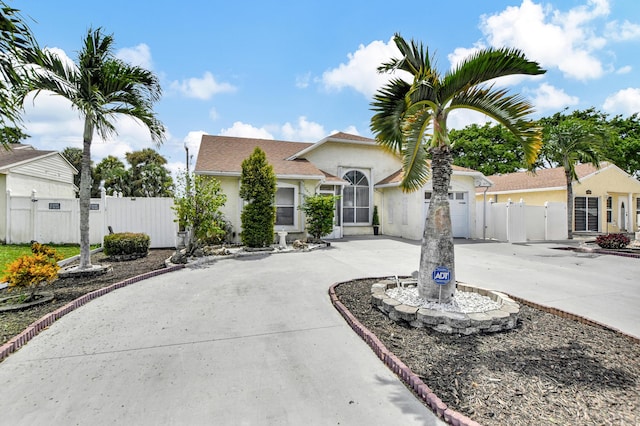 view of front of home featuring driveway, fence, a gate, and stucco siding