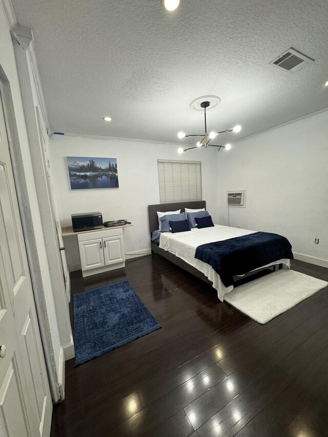 bedroom featuring dark wood-type flooring, visible vents, a textured ceiling, and baseboards