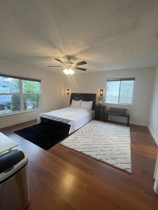 bedroom with ceiling fan, a textured ceiling, baseboards, and wood finished floors