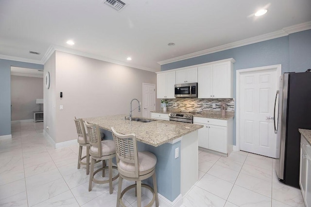 kitchen featuring sink, appliances with stainless steel finishes, white cabinetry, an island with sink, and decorative backsplash