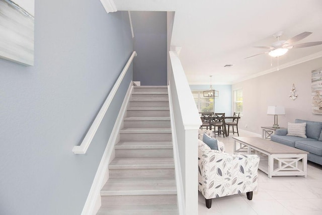 stairway with crown molding and ceiling fan