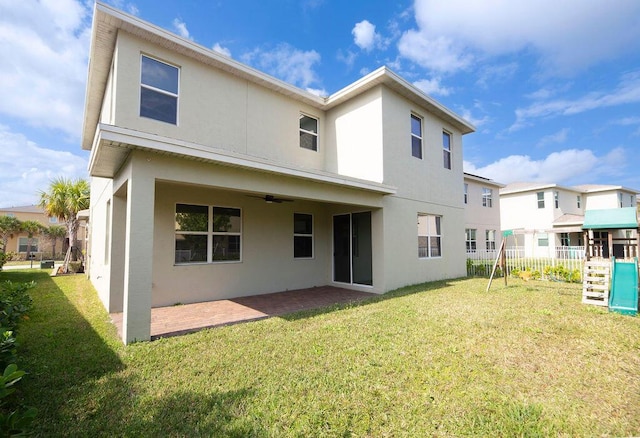 back of property with ceiling fan, a lawn, a patio, and a playground