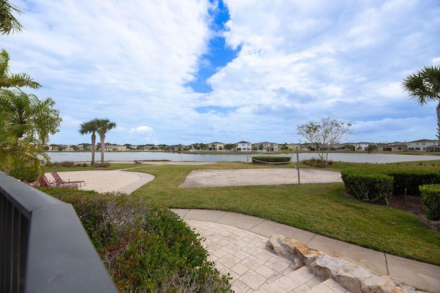 view of home's community with a water view, a yard, and volleyball court