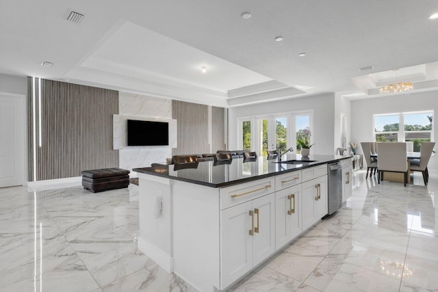 kitchen with white cabinetry, a tray ceiling, an island with sink, and a healthy amount of sunlight