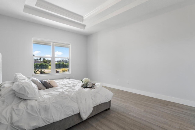 bedroom with a raised ceiling, crown molding, and hardwood / wood-style flooring