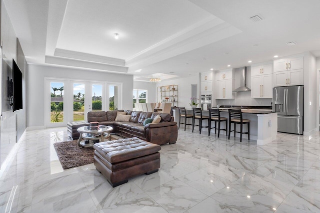 living room with french doors, a healthy amount of sunlight, and a tray ceiling