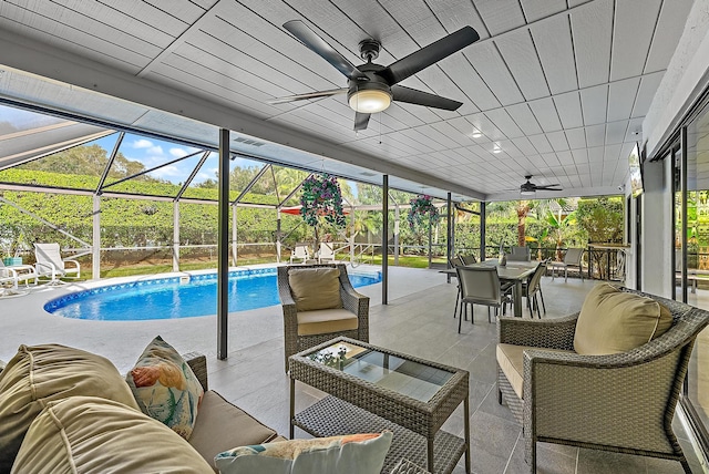 pool with a patio, glass enclosure, outdoor lounge area, and a ceiling fan