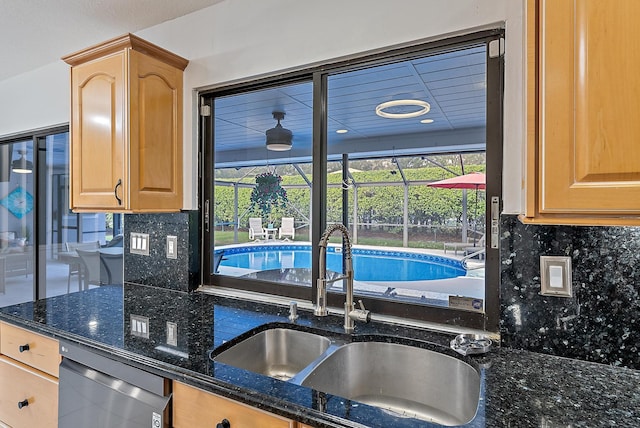 kitchen with dishwasher, tasteful backsplash, dark stone counters, and a sink