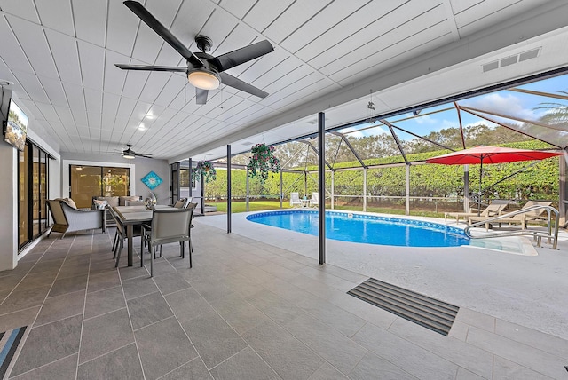 pool with outdoor dining area, a patio area, a lanai, and a ceiling fan