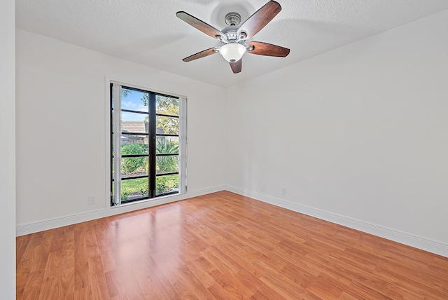 empty room featuring light wood finished floors, ceiling fan, baseboards, and a textured ceiling