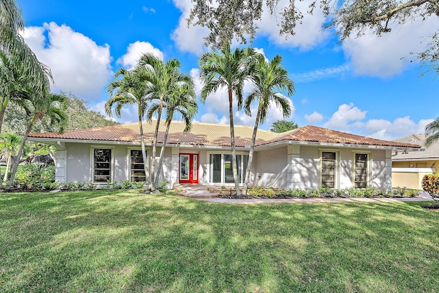 view of front facade featuring a front yard, a tile roof, and stucco siding