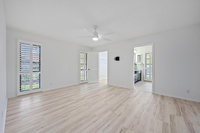 spare room featuring a healthy amount of sunlight, ceiling fan, light wood-style flooring, and baseboards