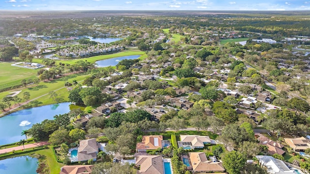 drone / aerial view featuring golf course view, a water view, and a residential view