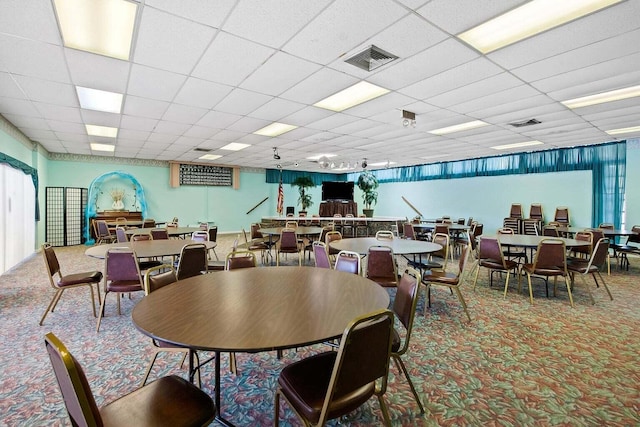 carpeted dining space with a paneled ceiling