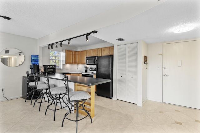 kitchen featuring backsplash, light tile patterned floors, a textured ceiling, and black appliances