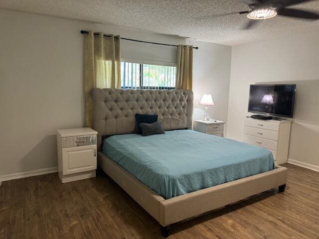 bedroom featuring a textured ceiling, dark wood-style flooring, and baseboards