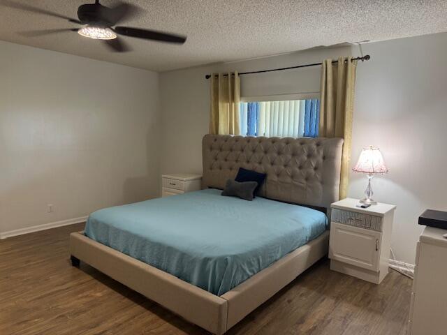 bedroom featuring dark wood-type flooring, ceiling fan, a textured ceiling, and baseboards