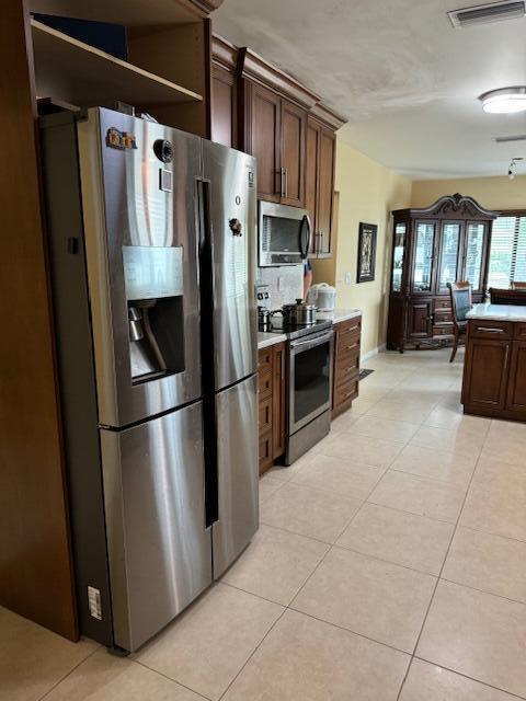 10298 Greentrail Dr N, Boynton Beach, FL 33436 - kitchen featuring appliances with stainless steel finishes, light tile patterned floors, light countertops, and dark brown cabinets